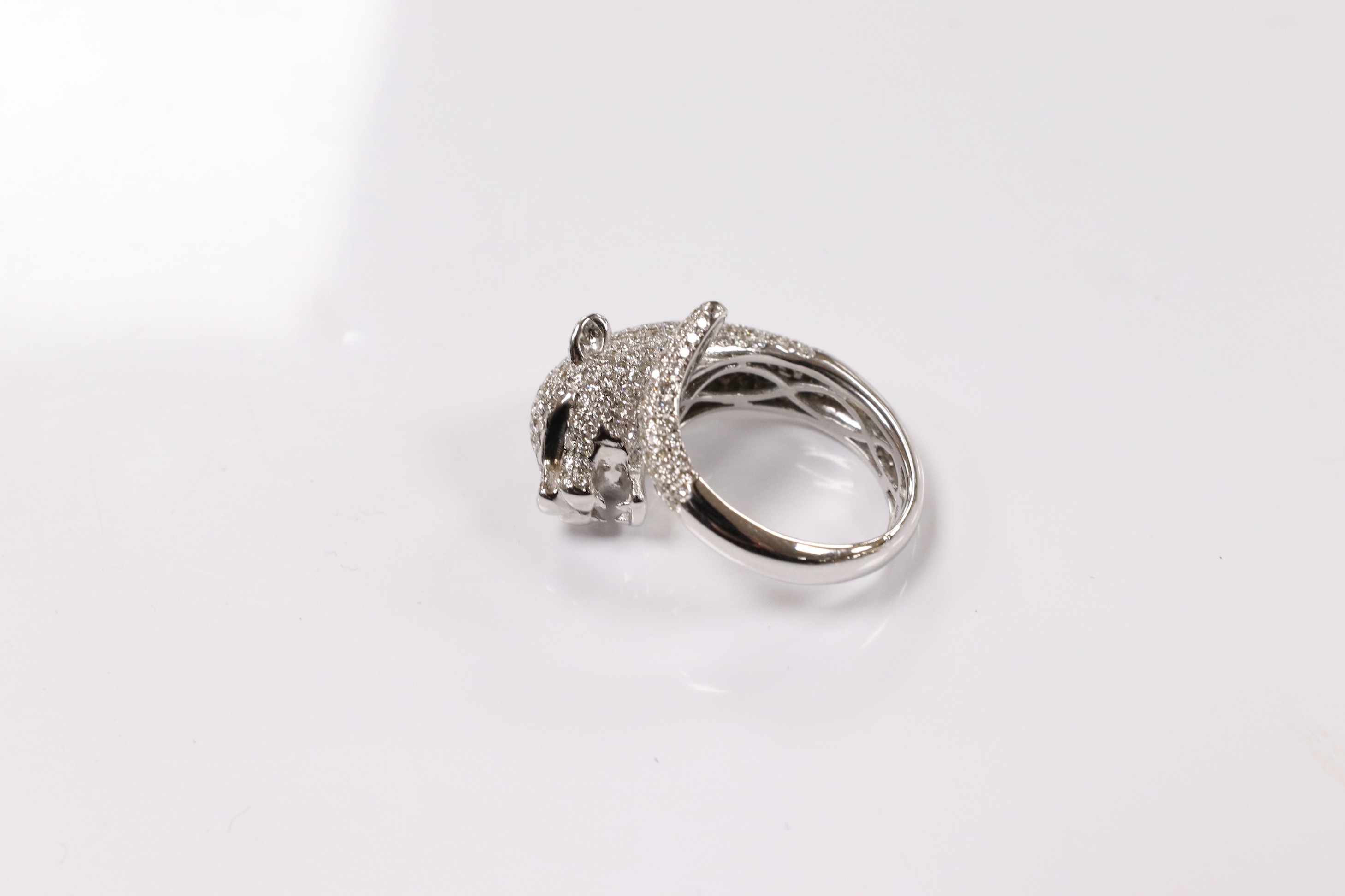 A modern Cartier style 18k white metal and pave set diamond chip dress ring, modelled as the head and tail of a leopard, size M, gross 9 grams. Condition - good